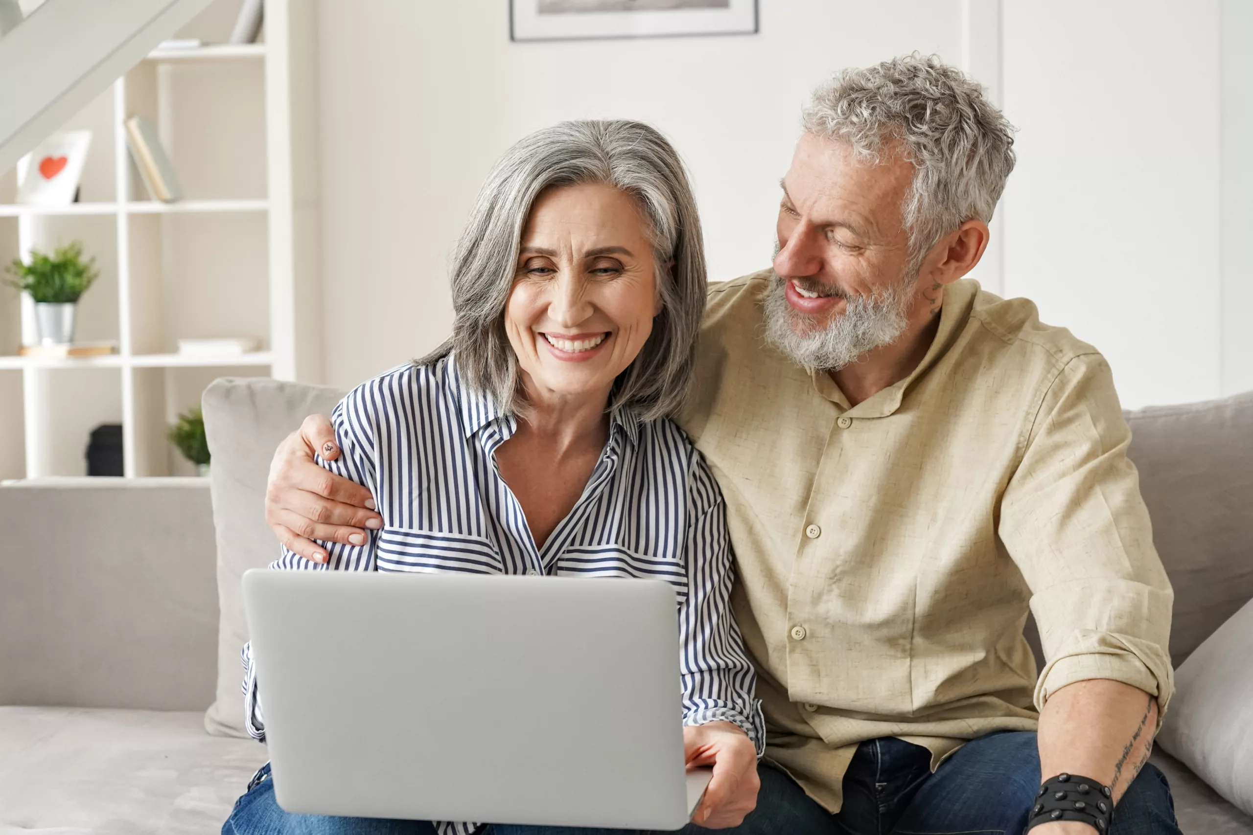 Happy,Mature,Mid,Age,Couple,Using,Laptop,Sit,On,Sofa